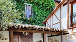 Un patio tradicional con una puerta de madera, dos sillas ornamentadas y un banco.