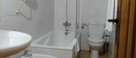 A bathroom with a bathtub, a shower, a toilet, and a bidet.