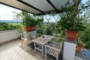 A balcony with a table and chairs, potted plants, and a view of the countryside. - Axia Terme B&B (Viterbo)