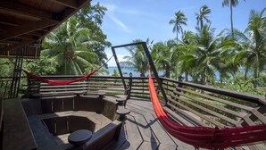 Une terrasse en bois avec un hamac, un coin salon et un jacuzzi.