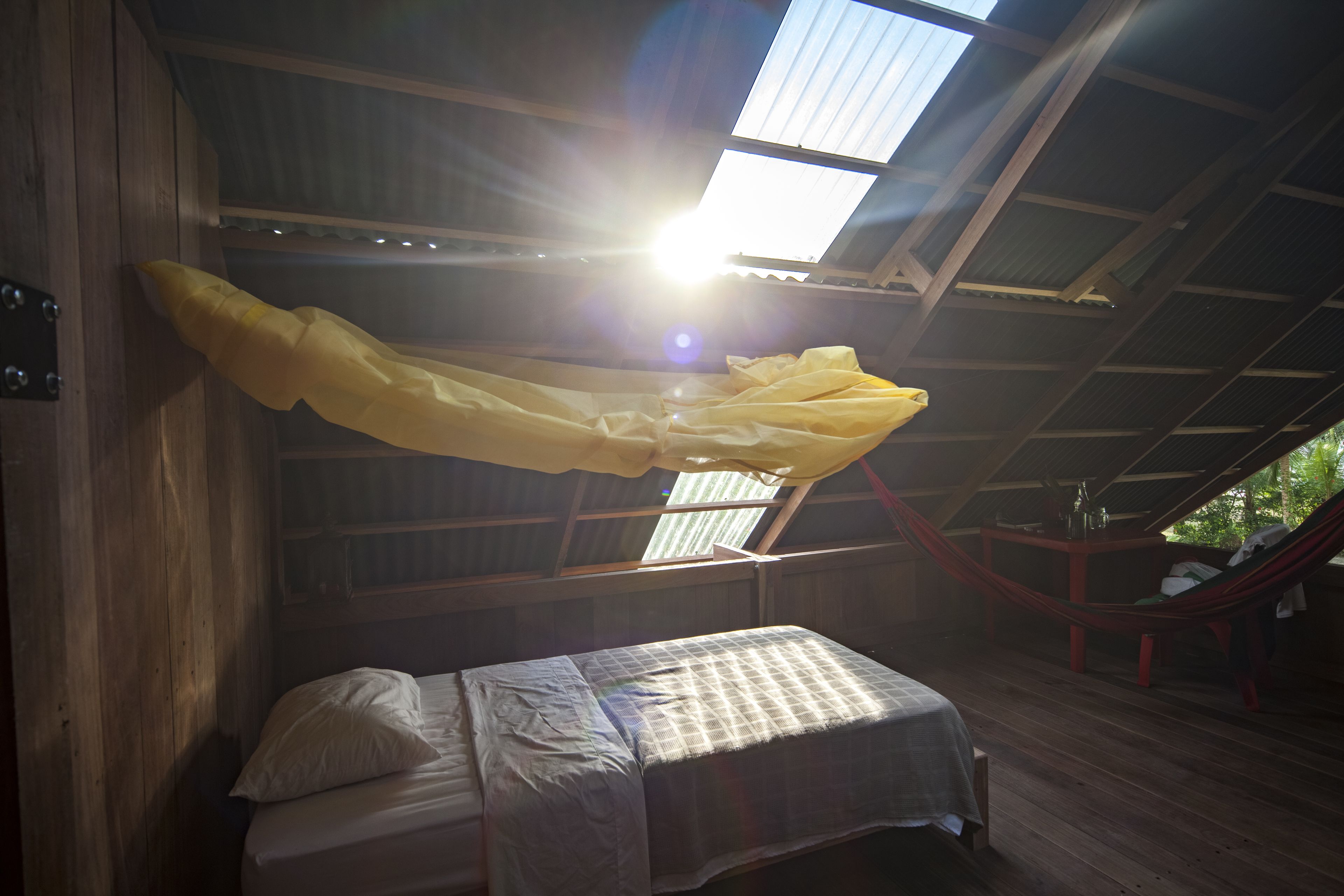 A room with a bed, a hammock, and a skylight.