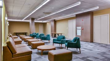 Un hall d’hôtel avec des canapés, des fauteuils, une table basse et une table entourée de chaises.