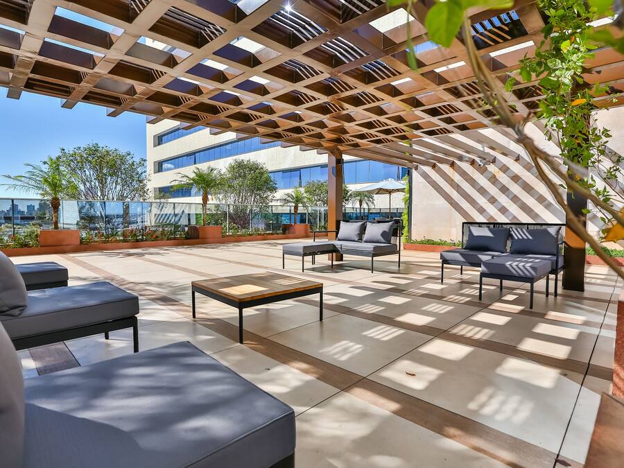 An outdoor patio with modern furniture, a pergola, and a view of the city skyline.