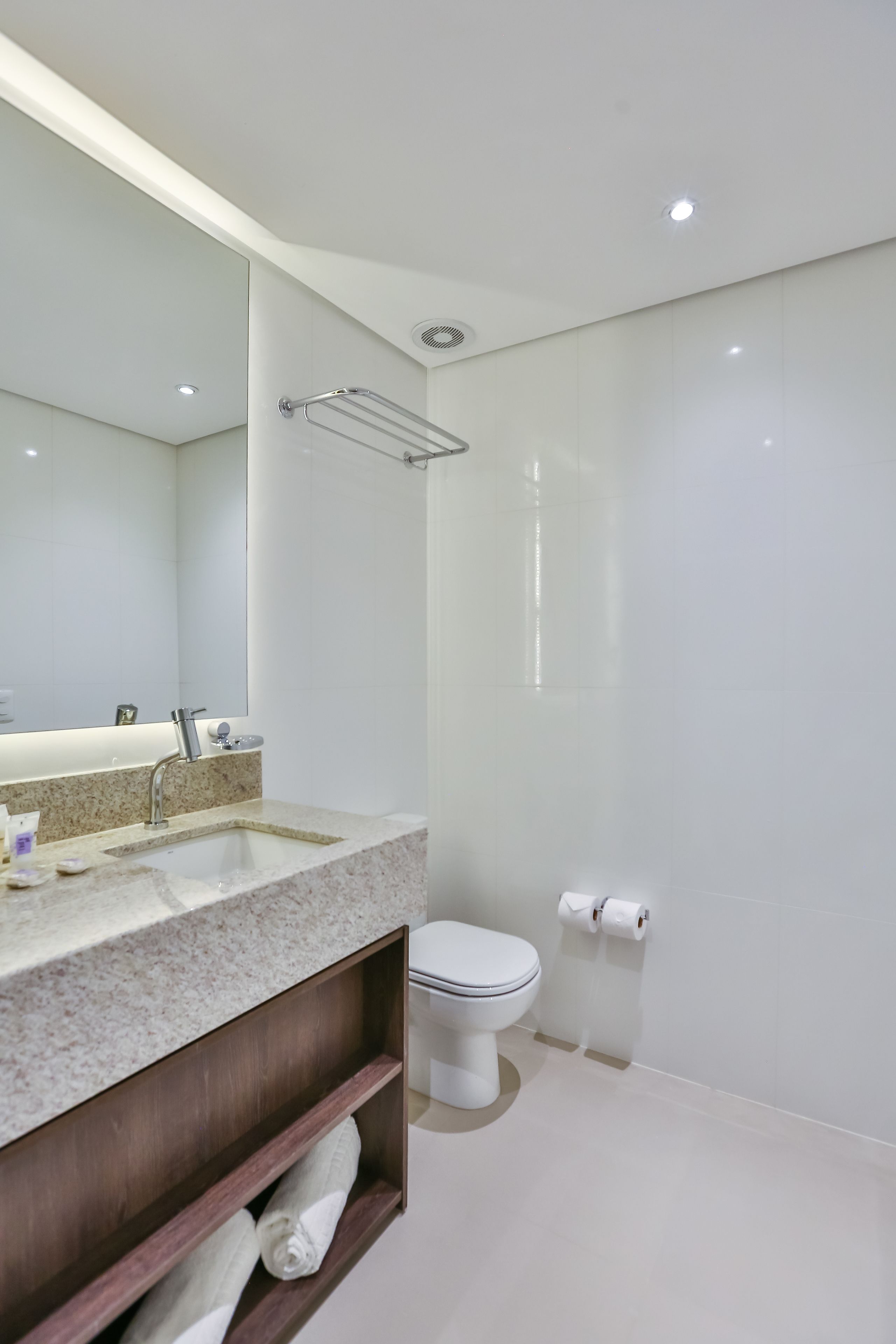 Une salle de bain moderne avec un grand miroir, un lavabo, des toilettes et une douche.