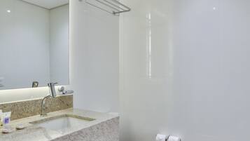 Une salle de bain moderne avec un grand miroir, un lavabo, des toilettes et une douche.