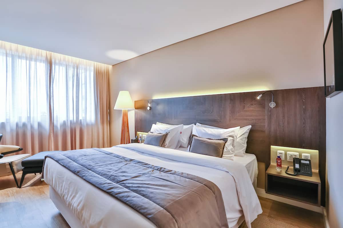Una camera d'albergo con un letto grande, comodini, una lampada e un telefono.