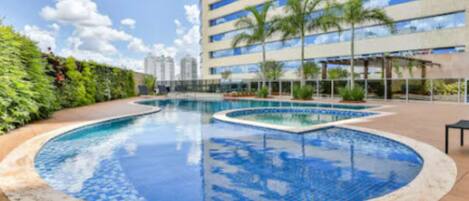 Een buitenzwembad, ligstoelen bij het zwembad