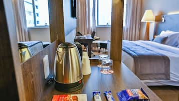 A hotel room with a bed, a desk, a coffee maker, and some snacks on the table.