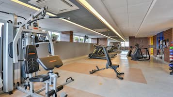 Un gimnasio con diversos equipos de ejercicio, incluyendo una máquina de pesas y cintas de correr.