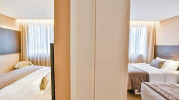 Habitación de hotel con dos camas, un escritorio y un amplio ventanal con cortinas.