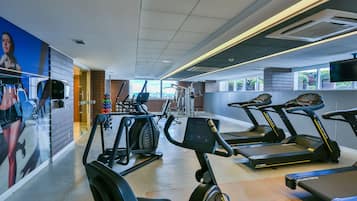 Uma academia com esteiras, bicicletas ergométricas e equipamentos de exercícios.