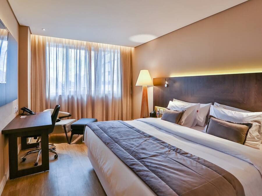 Une chambre d’hôtel avec un grand lit, un bureau, une chaise et une lampe.
