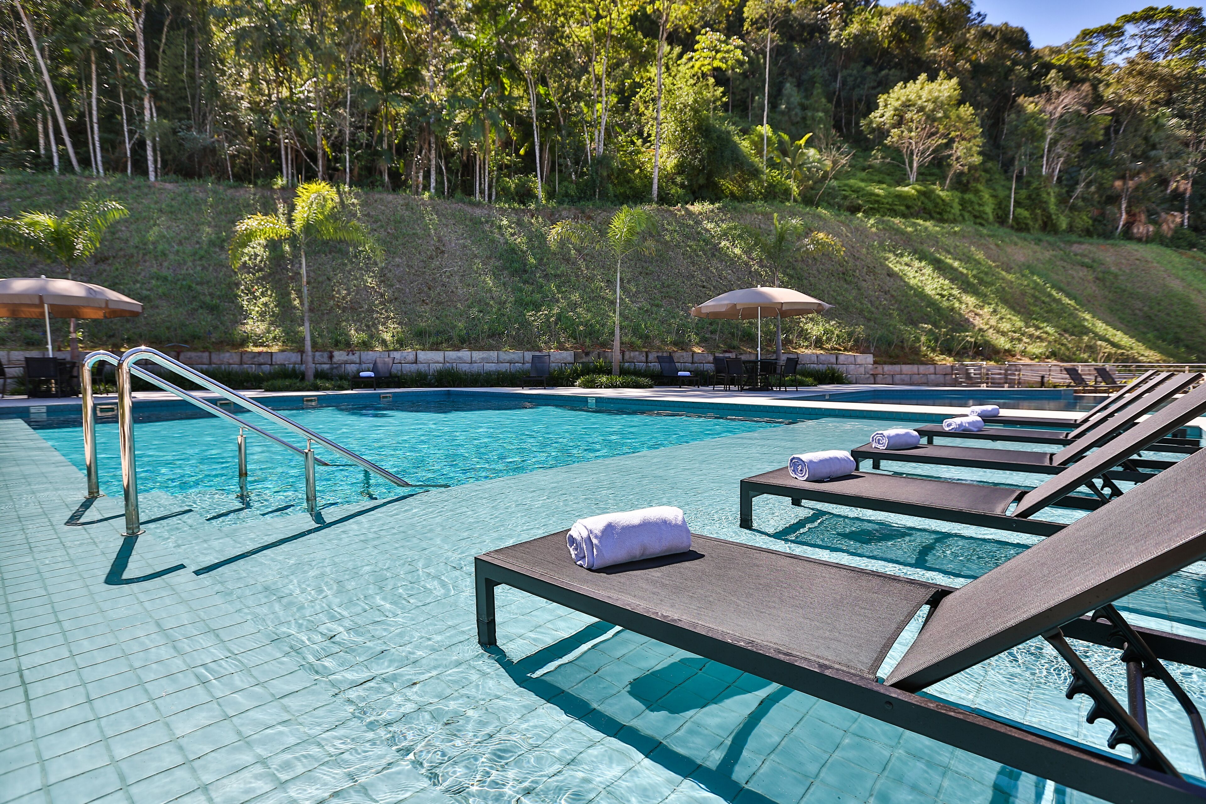 A pool area with lounge chairs, a diving board, and umbrellas.