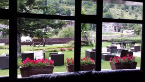 A view through a window with wicker furniture and flower planters. - Roca Blanca (Espot)