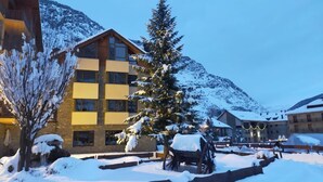 A snow-covered courtyard with a wooden building, a snow-laden tree, and a snow-covered cart. - Roca Blanca (Espot)