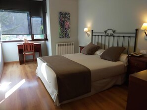 A bedroom with a bed, bedside table, lamp, chair, and a window.
