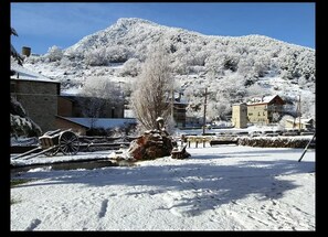 A snow-covered landscape with buildings, a stone wall, and a wooden cart.
