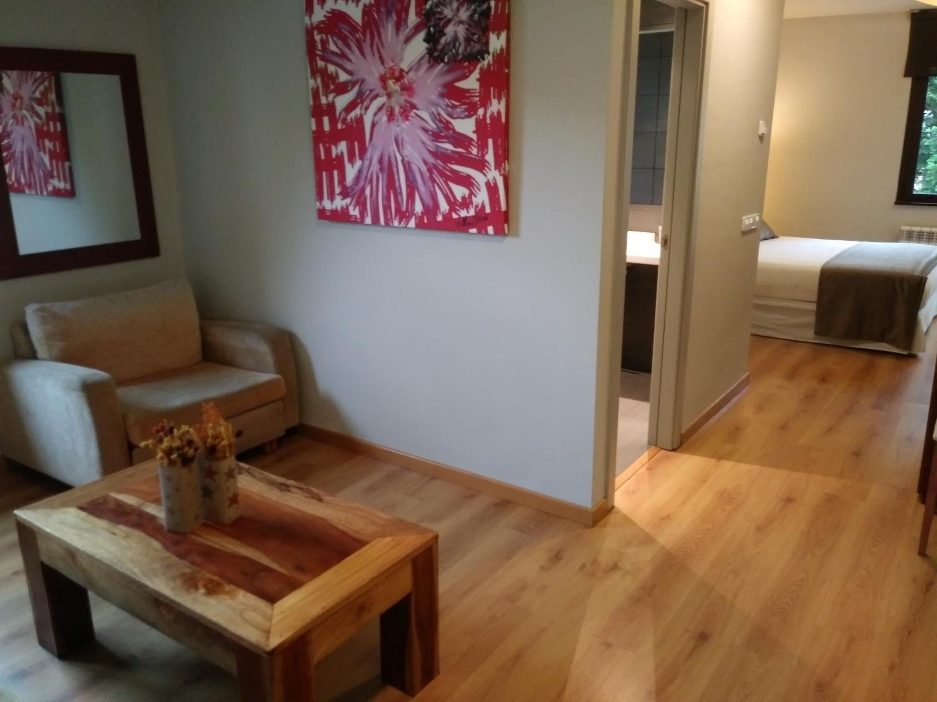 Un salón con una mesa de centro de madera, un sofá color beige y un cuadro abstracto de gran tamaño en la pared.