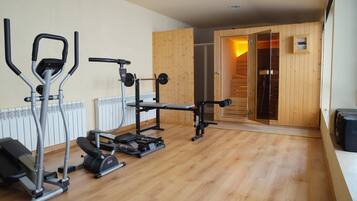 Een fitnessruimte met trainingsapparatuur, een bank en een sauna.