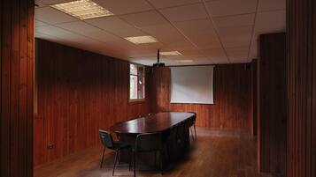 Un salón de conferencias con pared de paneles de madera, una mesa grande y sillas.