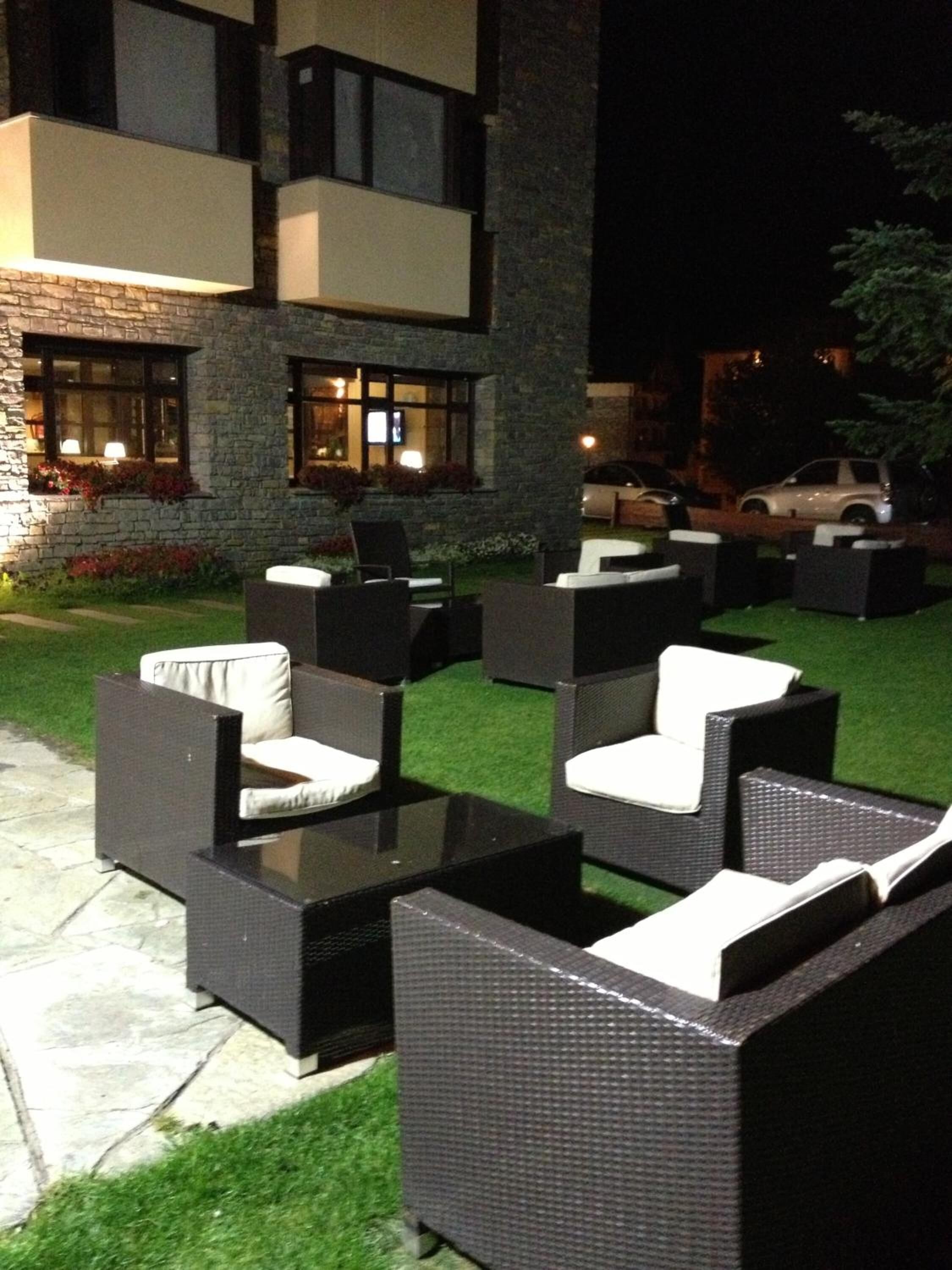 An outdoor seating area with wicker furniture and a stone building in the background.