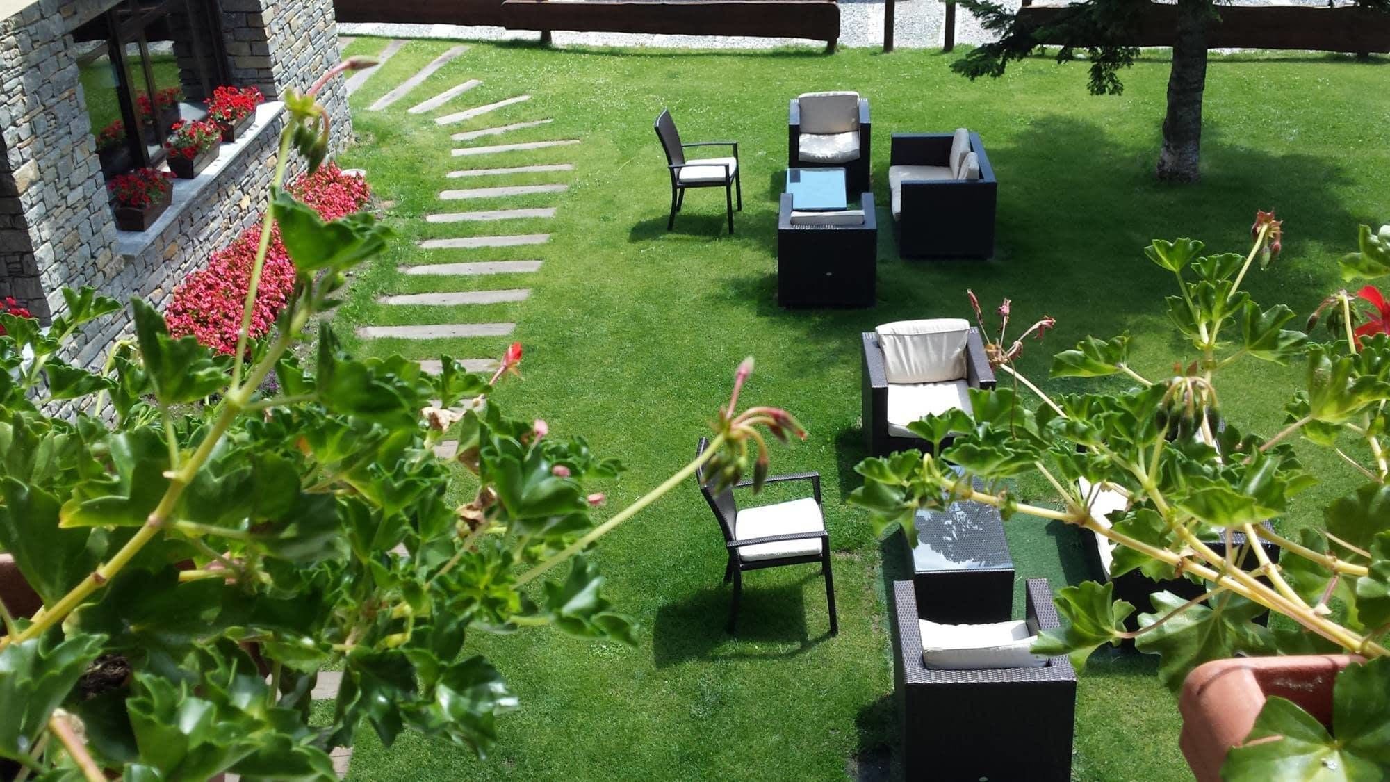 A patio with outdoor furniture, a stone wall, and a garden with red flowers.