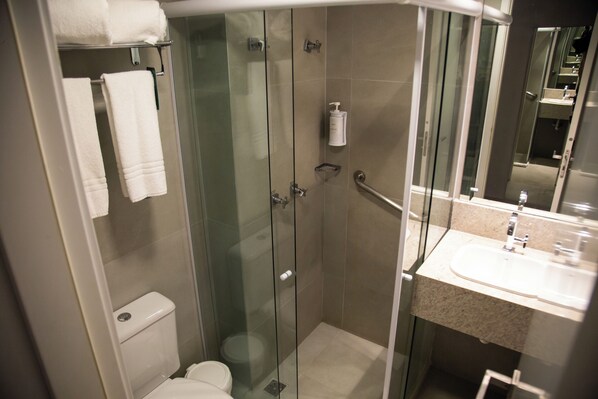 A modern bathroom with a glass-enclosed shower, a toilet, and a sink with a mirror.
