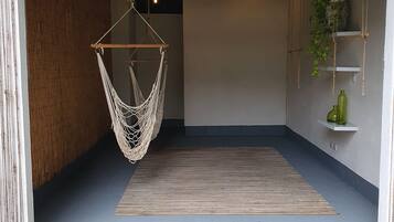 Amplio espacio interior con una hamaca colgante, piso de madera y piso de concreto que da al exterior.
