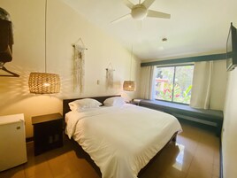 Un dormitorio con cama, ventilador de techo, ventana con cortinas y decoración en la pared.