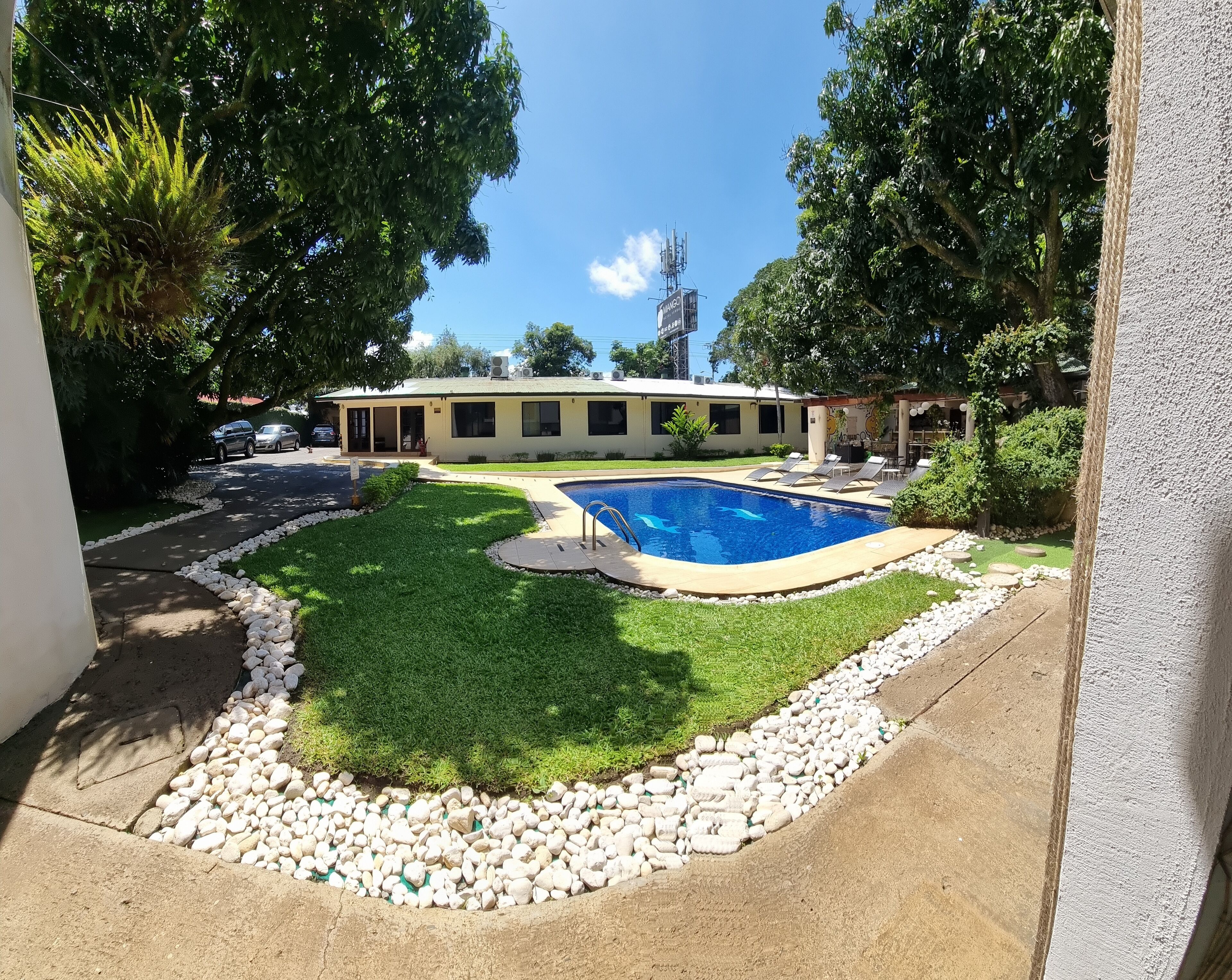 A residential property with a swimming pool, a covered patio, and a well-maintained lawn.