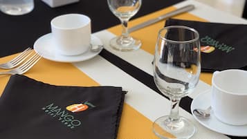 Une table dressée pour le repas, avec une serviette noire, une tasse blanche, un verre à vin et une fourchette.