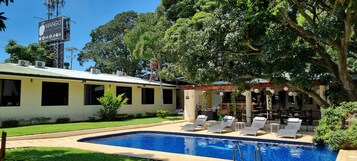 Un hotel con piscina, zona de estar al aire libre y un letrero.