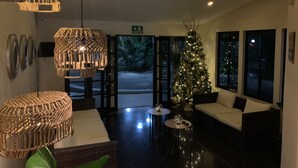 A lobby with a Christmas tree, wicker furniture, and a reception desk. - Hotel Mango (Rio Segundo)