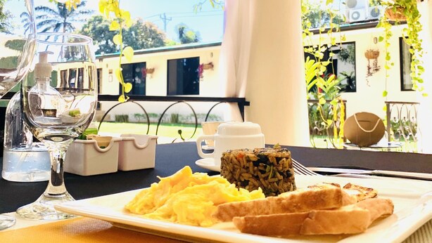 A dining table with a plate of food, a glass of water, and a cup. - Hotel Mango (Rio Segundo)
