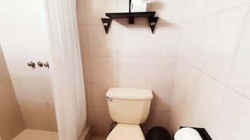 Un baño con inodoro, ducha, toallero y cubo de basura.