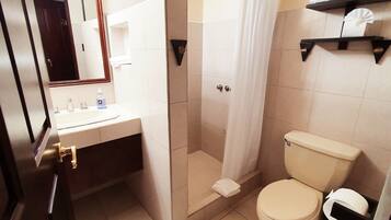 A bathroom with a toilet, a shower with a curtain, a sink with a mirror, and a towel rack.