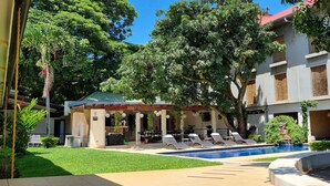 A hotel courtyard with a swimming pool, lounge chairs, and a covered seating area. - Hotel Mango (Rio Segundo)
