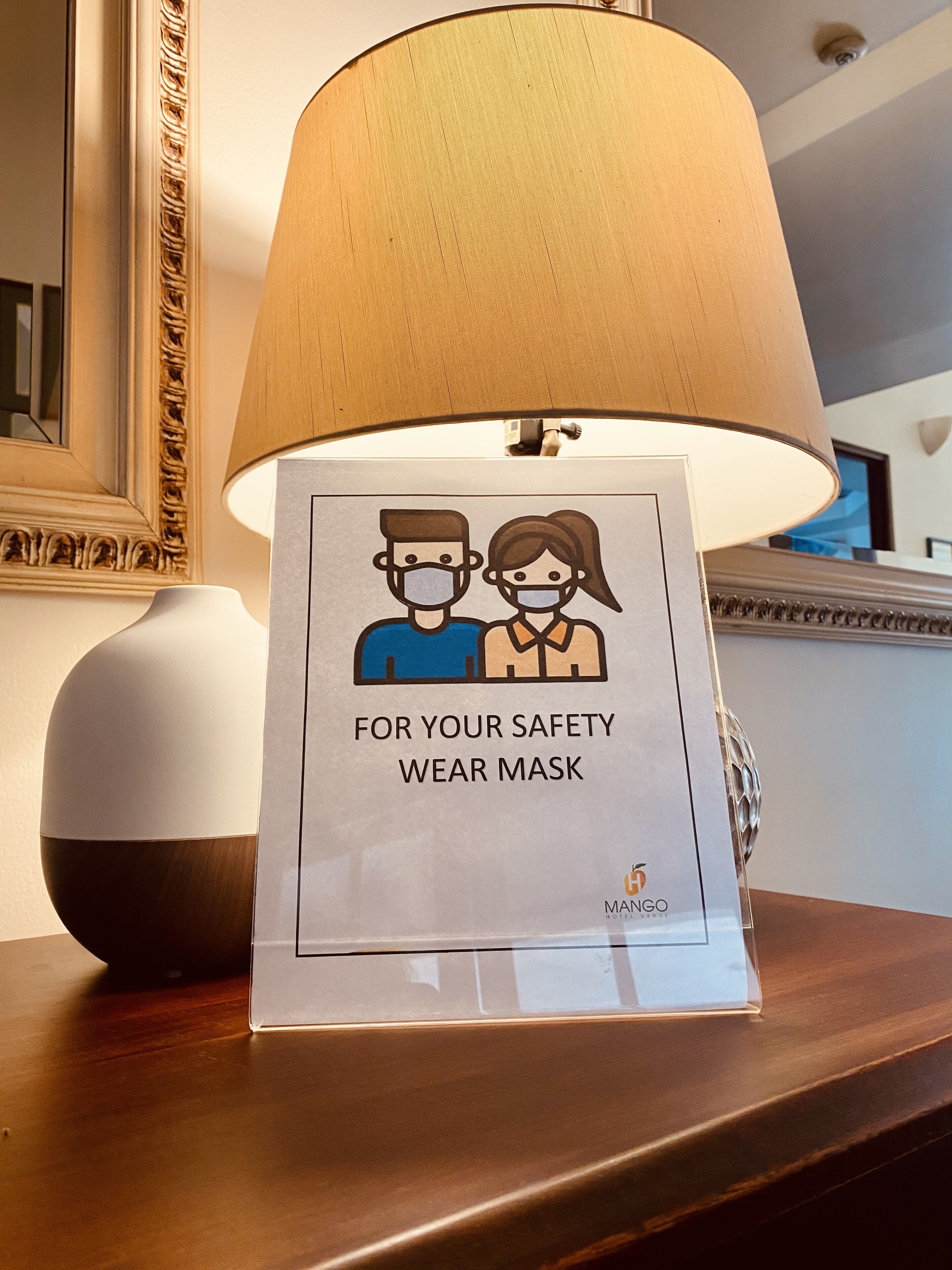 Une enseigne d’hôtel avec une illustration représentant un masque et le texte : « POUR VOTRE SÉCURITÉ, PORTEZ UN MASQUE ».