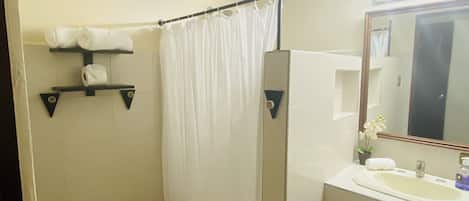 A bathroom with a toilet, shower curtain, sink, and mirror.