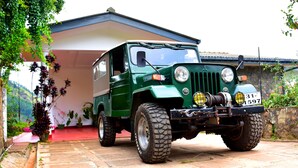 A green off-road vehicle parked in front of a building with a red carpet and potted plants.
