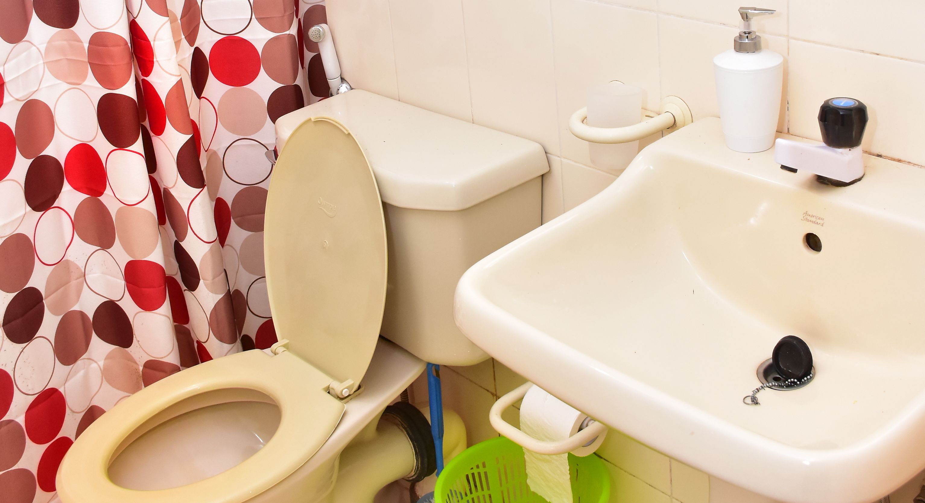 Un baño con inodoro, lavamanos y cortina de ducha.