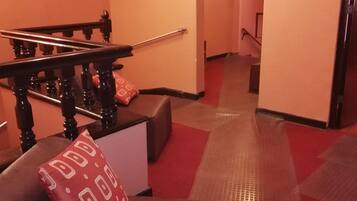 Un pasillo de hotel con una escalera, un detector de incendios y un letrero que dice 'SALIDA'.