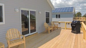 A deck with wooden chairs and a barbecue grill.