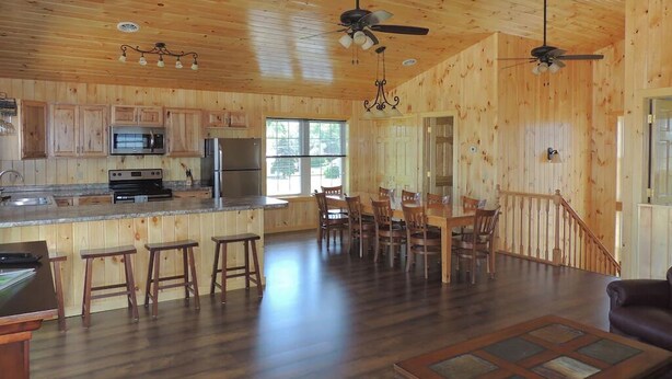 A spacious wooden cabin with a kitchen, dining area, and a staircase.