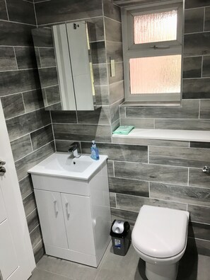 Un bagno con un lavandino bianco, uno specchio, una finestra e un water.