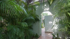 Un jardin luxuriant et verdoyant, avec un sentier qui traverse une arche en pierre.