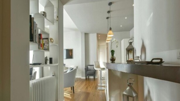 A modern kitchen with a bar area, a dining area with chairs, and a white radiator. - Apartments Florence - Ponte Vecchio Guelfo (Florence)