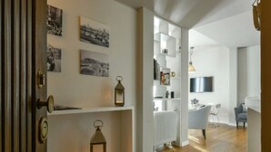 A modern interior with a wooden floor, white walls, and a dining area with a TV. - Apartments Florence - Ponte Vecchio Guelfo (Florence)