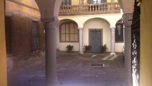 A courtyard with arches, a balcony, and potted plants. - Bergamo: House with character (Bergamo)