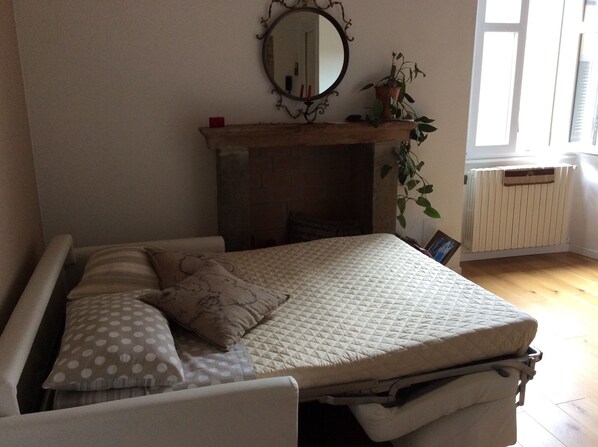 A bedroom with a bed, pillows, a mirror, a fireplace, and a window. - Bergamo: House with character (Bergamo)